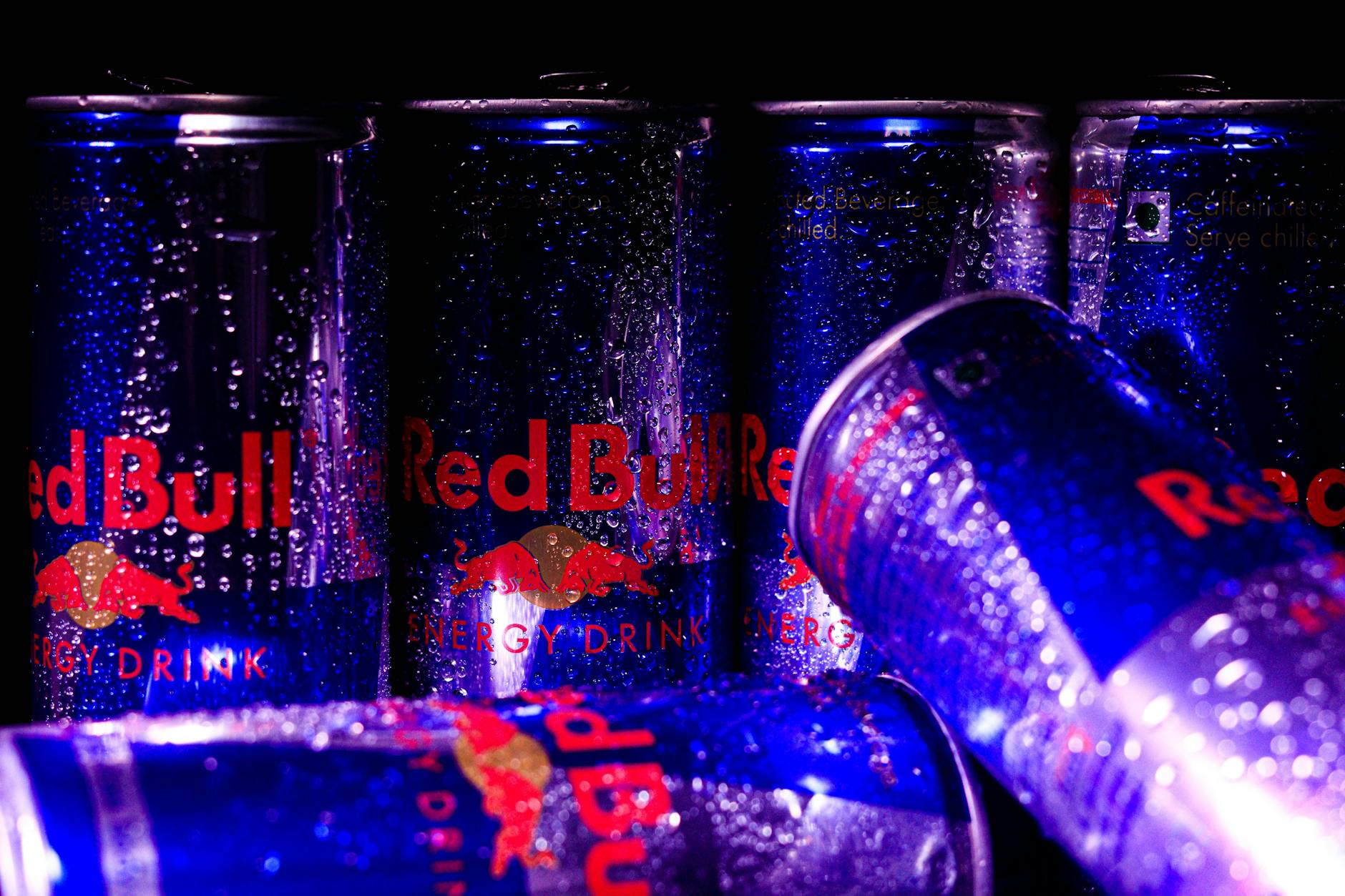Close-up of Red Bull cans with water droplets, showcasing a refreshing and energetic vibe.