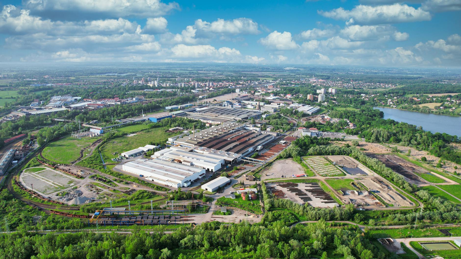 Drone view of Bohumín, showcasing industrial areas and green landscapes under a bright sky.