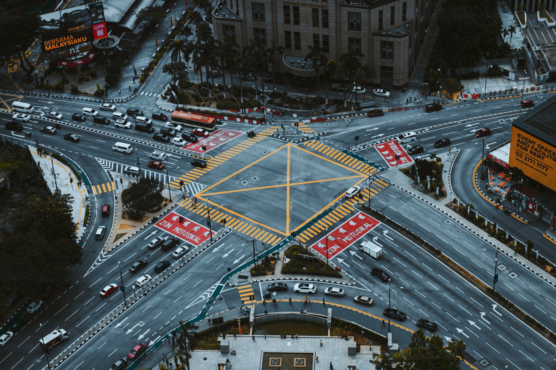 A bustling intersection in Kuala Lumpur at night, showcasing vibrant city life and modern architecture.