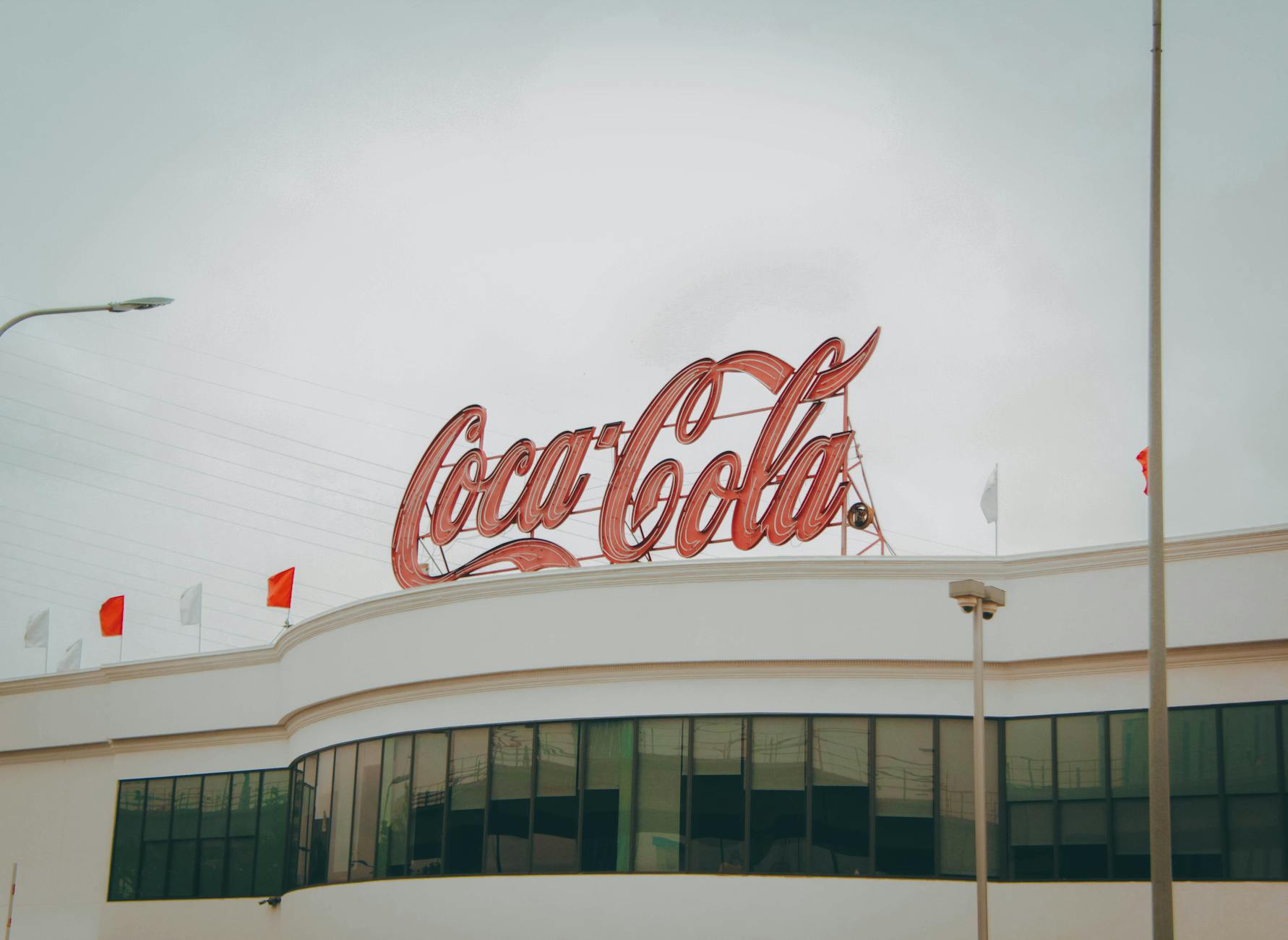 Exterior view of Coca-Cola factory with iconic red sign atop the modern building.